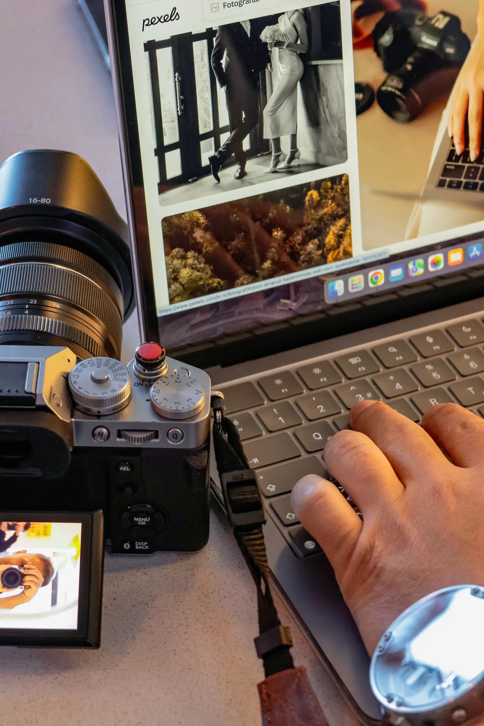 A photographer editing wedding photographs on a laptop beside camera equipment