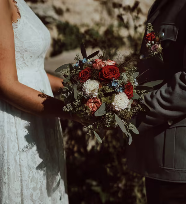 Wedding couple holding a richly colored floral bouquet